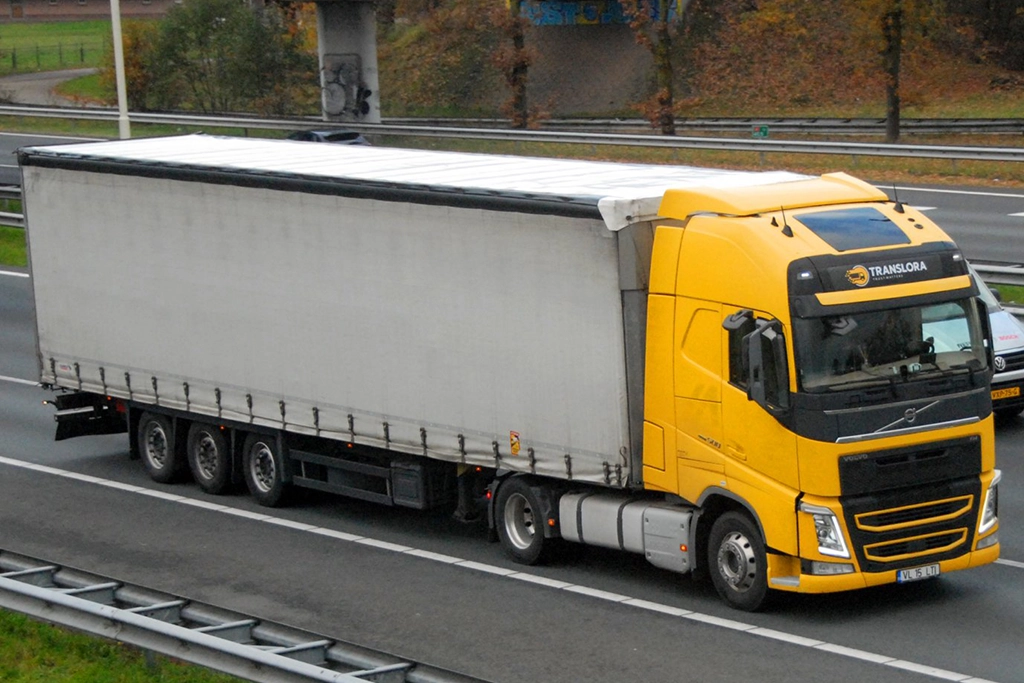 Camion Volvo galben si semiremorca cu prelata fotografiate pe autostrada